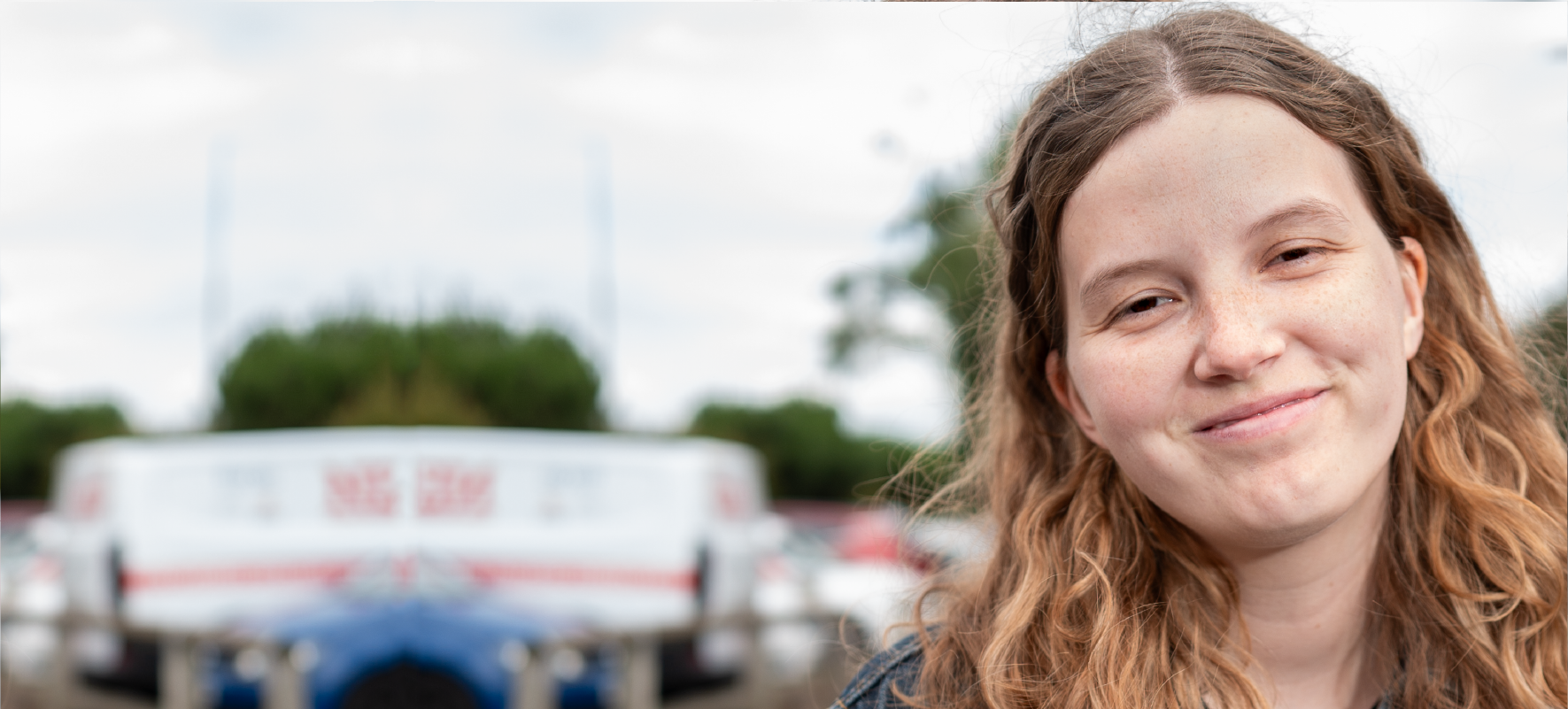 A photo of a young woman with long brown hair, gently smiling