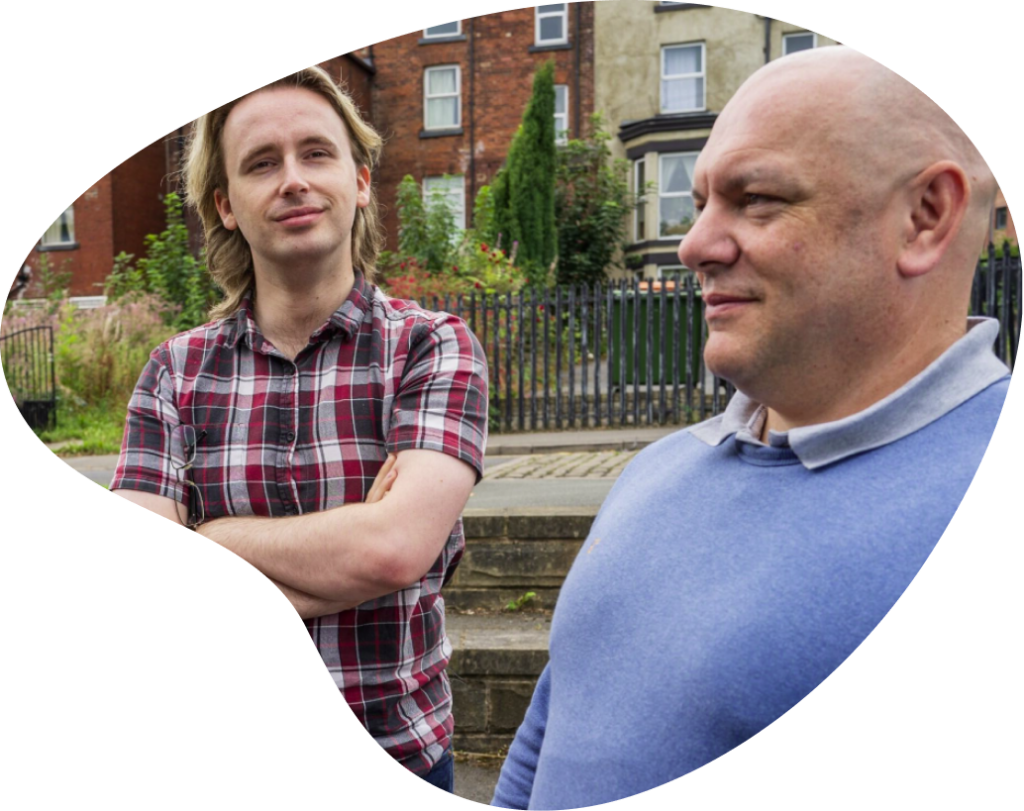 Two men standing together in front of housing