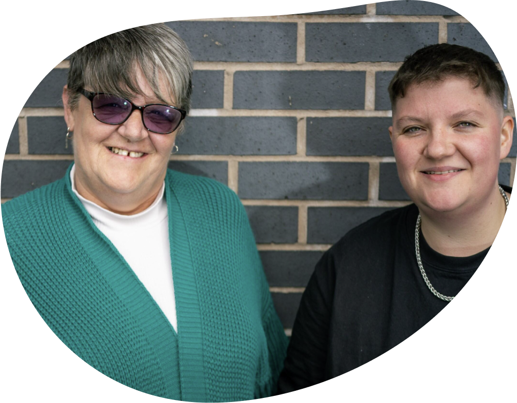 Two women standing in front of a brick wall smiling